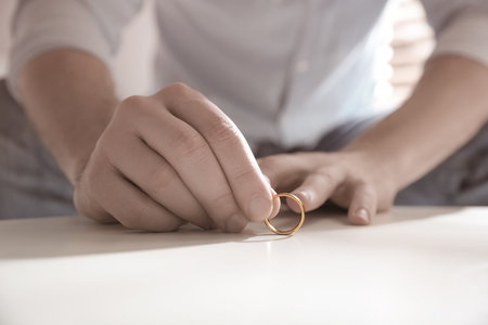 Man with wedding ring at table indoors, closeup. Cheating and breakupの写真素材