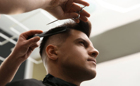 Professional barber making stylish haircut in salon, closeupの写真素材