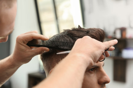 Professional barber making stylish haircut in salon, closeupの写真素材
