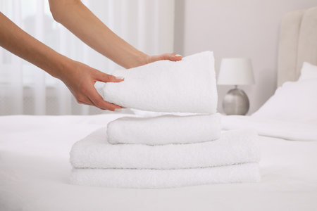 Chambermaid putting fresh towels on bed in hotel room, closeupの写真素材
