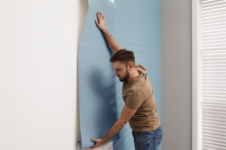 Man stylish hanging wall paper sheet indoors