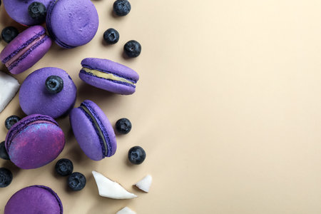 Flat lay composition with purple macarons, blueberries and pieces of coconut on beige background. Space for textの写真素材