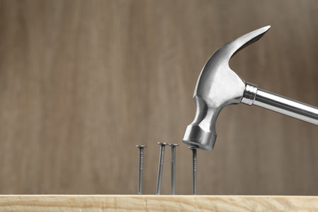 Hammering nail into plank against wooden background, space for textの写真素材