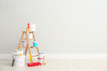 Decorator's kit of tools and paints near light wall indoors. Space for textの写真素材