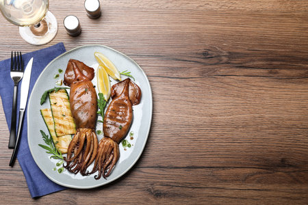 Delicious grilled squids served on wooden table, flat lay. Space for textの写真素材