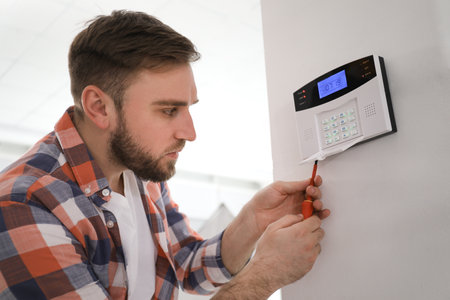 Man installing home security system on white wall in roomの写真素材