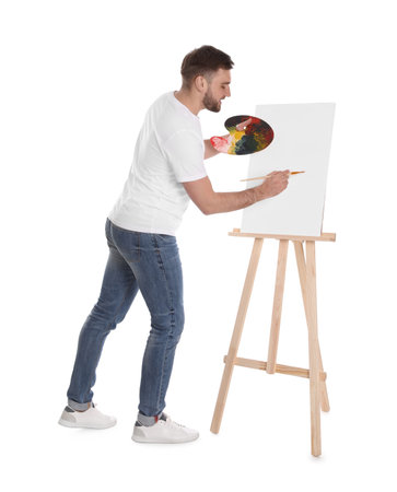 Man painting with brush on easel against white background. young artistの写真素材