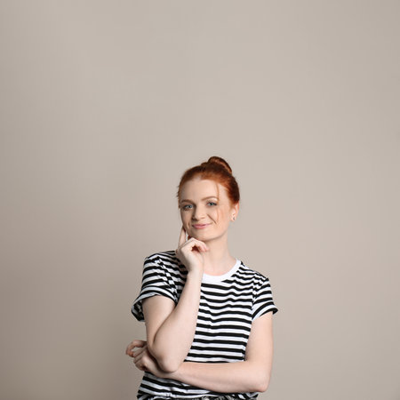 Candid portrait of happy red haired woman with charming smile on beige backgroundの写真素材