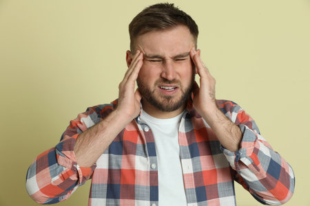 Man suffering from migraine on light green backgroundの写真素材
