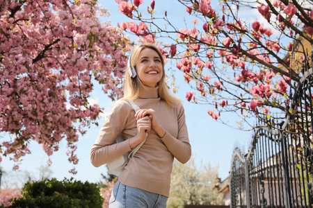 Happy woman with headphones listening to audiobook outdoors on spring dayの写真素材