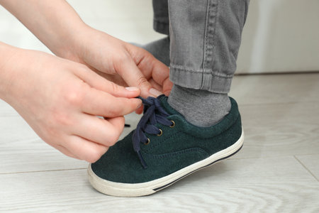Mother helping son to tie shoe laces at home, closeupの写真素材