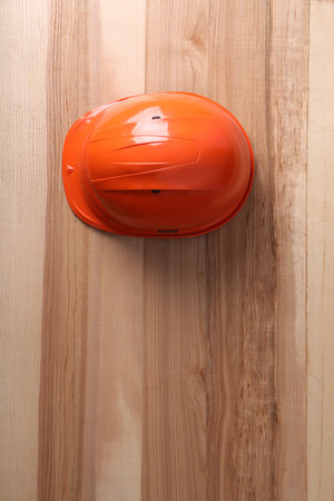 Orange hard hat on wooden background, top view. Space for textの写真素材