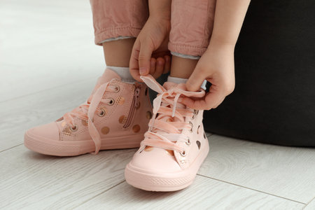 Little girl tying shoe laces at home, closeupの写真素材