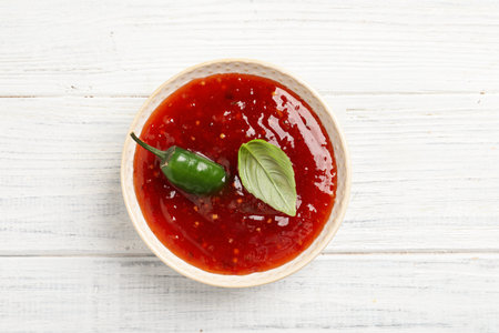 Spicy chili sauce with basil on white wooden table, top viewの写真素材