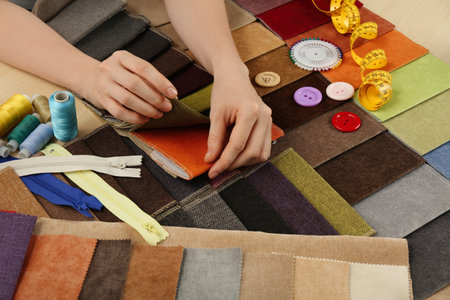 Woman choosing among colorful fabric samples, closeup