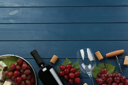 Tasty red wine and snacks on blue wooden table, flat lay. Space for textの写真素材