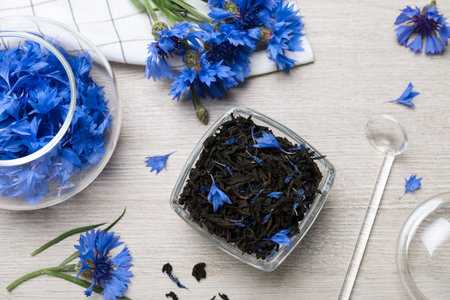 Composition with dry tea leaves and cornflowers on white wooden table, flat layの写真素材