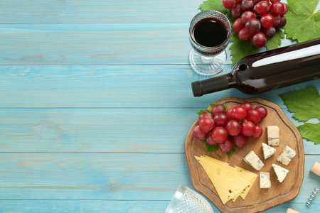 Tasty red wine and snacks on light blue wooden table, flat lay. Space for textの写真素材