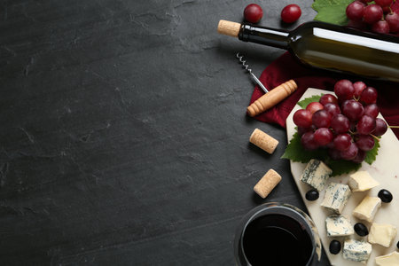 Tasty red wine and snacks on black table, flat lay. Space for textの写真素材
