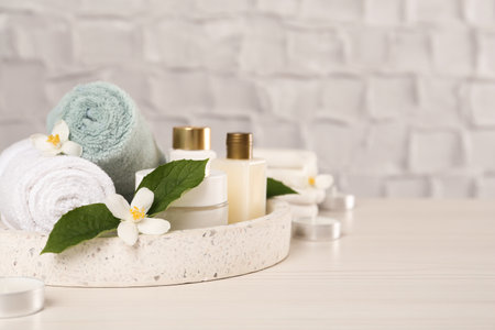 Beautiful jasmine flowers, towels and skin care products on white wooden table, space for textの写真素材