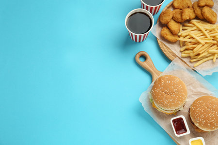 Different fast food on turquoise background, flat lay. Space for textの写真素材