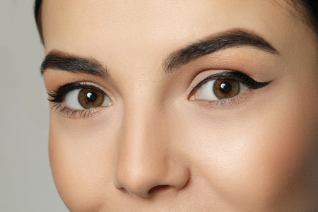 Young woman with beautiful eyebrows on gray background, closeupの写真素材