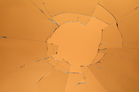 Closeup view of broken glass with cracks on orange backgroundの写真素材