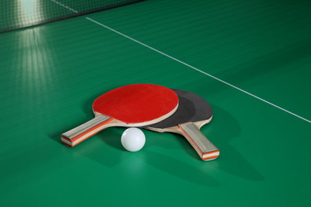 Rackets and ball on green table tennis table