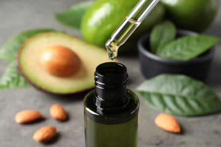 Dripping avocado essential oil into bottle on table, closeupの写真素材