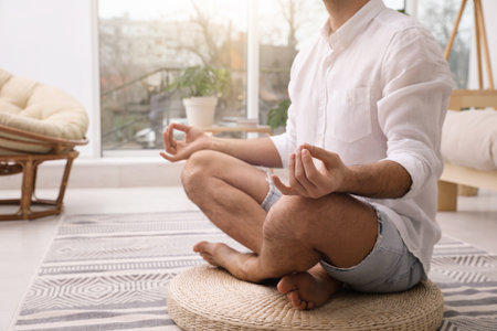 Man meditating on wicker mat at home, closeupの写真素材