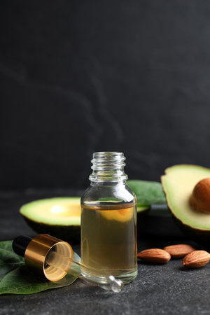 Essential oil, avocado and almonds on black table. Space for textの写真素材