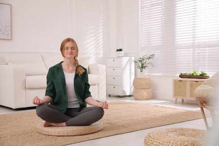 Woman meditating on wicker mat at home. Space for textの写真素材