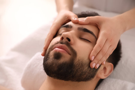 Young man receiving facial massage in beauty salon, closeupの写真素材