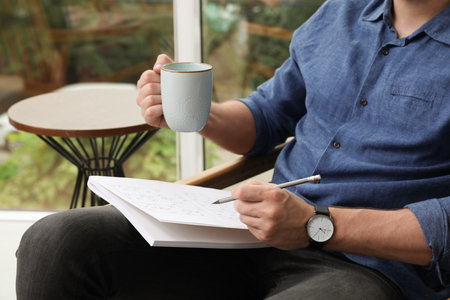 Man solving sudoku puzzle at home, closeupの写真素材