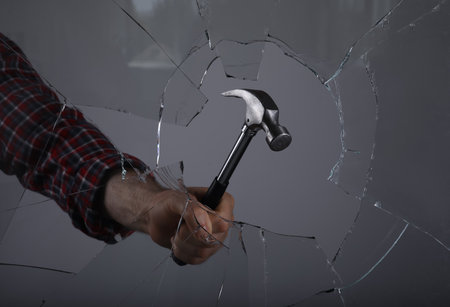 Man breaking window with hammer on grey background, closeupの写真素材