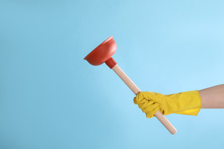 Woman holding plunger on turquoise background, closeup. Space for textの写真素材