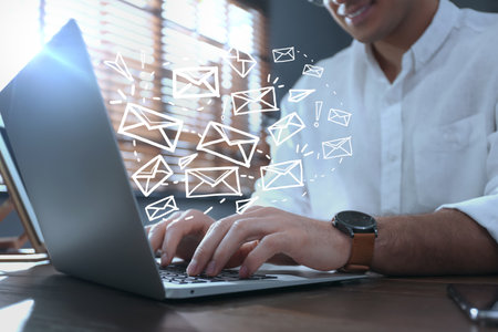 Businessman sending emails at table indoors, closeupの写真素材