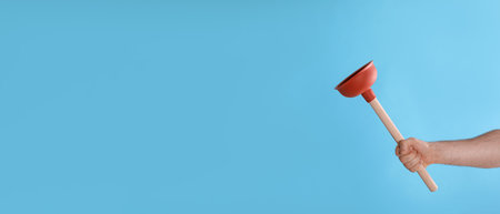 Man holding plunger on turquoise background, closeup. Space for textの写真素材