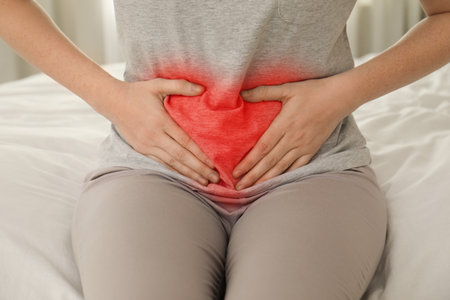 Woman suffering from abdominal pain on bed at home, closeupの写真素材