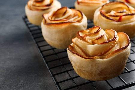 Cooling rack with freshly baked apple roses on gray table, closeup. beautiful dessertの写真素材