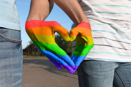 Gay couple forming heart with hands in park, closeupの写真素材