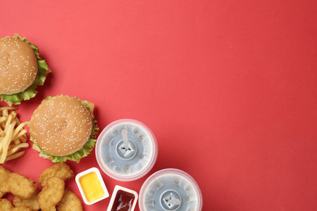 Flat lay composition with delicious fast food menu on red background. Space for textの写真素材