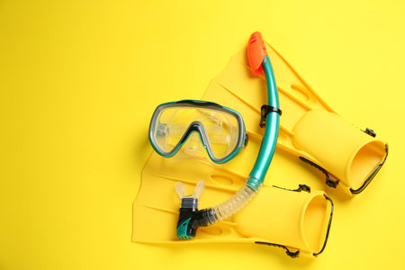 Pair of flippers and mask on yellow background, flat lay. Space for textの写真素材