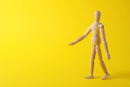 Wooden human model on yellow background, space for text. Mini mannequinの写真素材