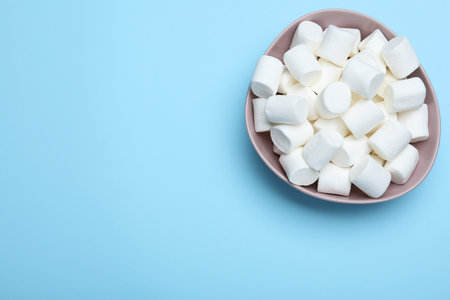 Delicious puffy marshmallows on light blue background, top view. Space for textの写真素材