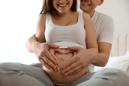 Young pregnant woman with her husband indoors, closeupの写真素材