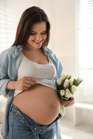 Young pregnant woman with flowers at homeの写真素材