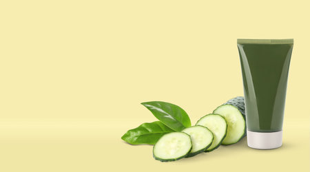 Makeup remover, fresh cucumber and green leaves on yellow background. Space for textの写真素材