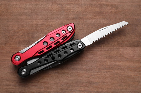 Modern compact portable multitool on wooden table, top view