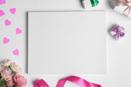 Flat lay composition with blank canvas, gift boxes and beautiful roses on white background. Mockup for designの写真素材